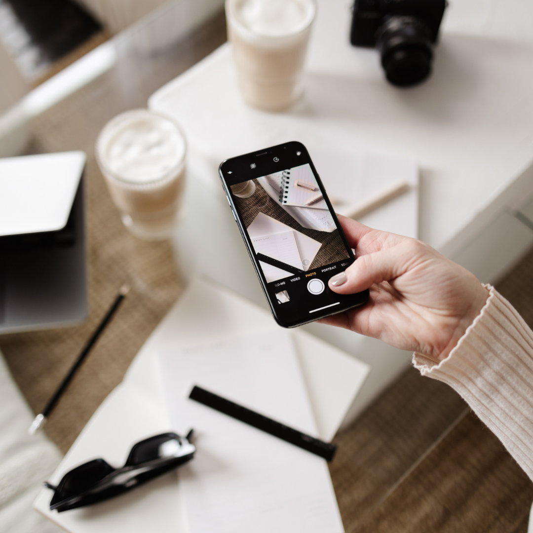 A person holding a smartphone with social media icons in the background.